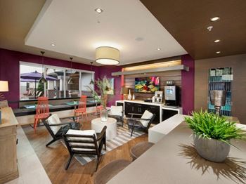 a hotel lobby with purple walls and a white table and chairs at The Rialto, Orlando, FL, 32819